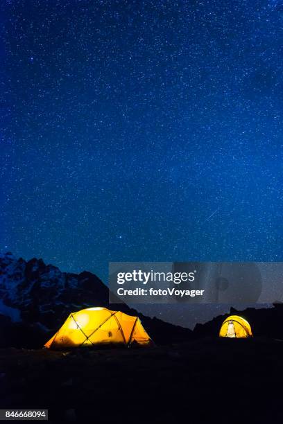 stars shining night sky over illuminated mountain tents himalayas nepal - camping selvagem imagens e fotografias de stock