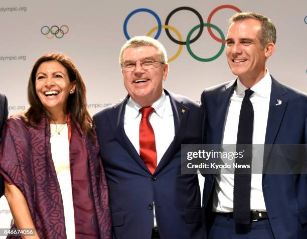 Thomas Bach , president of the International Olympic Committee, Paris Mayor Anne Hidalgo and Los Angeles Mayor Eric Garcetti smile at a press...