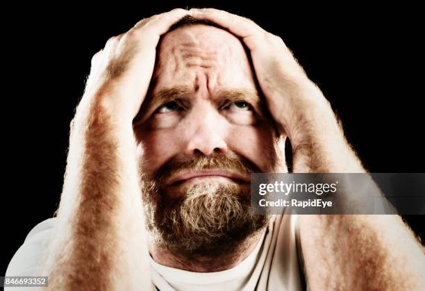 mature man holding his head, grimacing in agony or terror - glaring meaning stock pictures, royalty-free photos & images