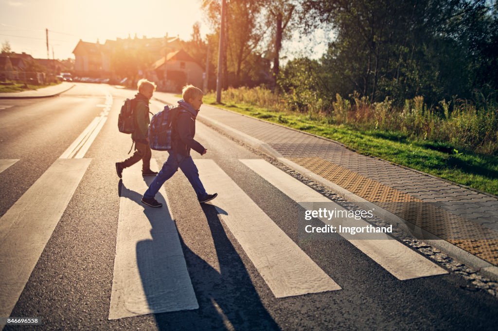 Schule Jungs gehen auf Zebrastreifen auf Schulweg