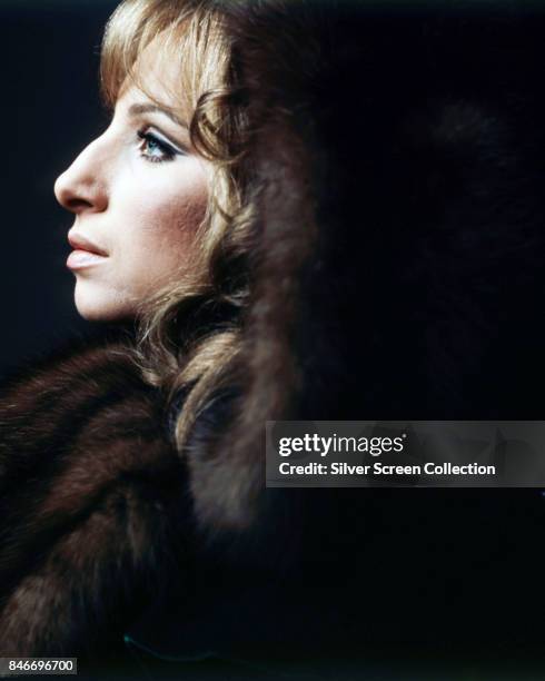American singer and actress Barbra Streisand as she poses wearing a fur coat, circa 1970.