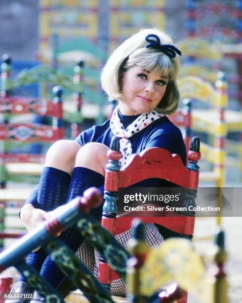 American actress and singer Doris Day hugging her keens while sitting on a chair,circa 1955.