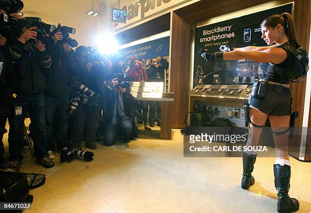 Model Alison Carroll poses with mobile phones as film and computer games character Lara Croft during a photocall in London, on February 6, 2009. The...