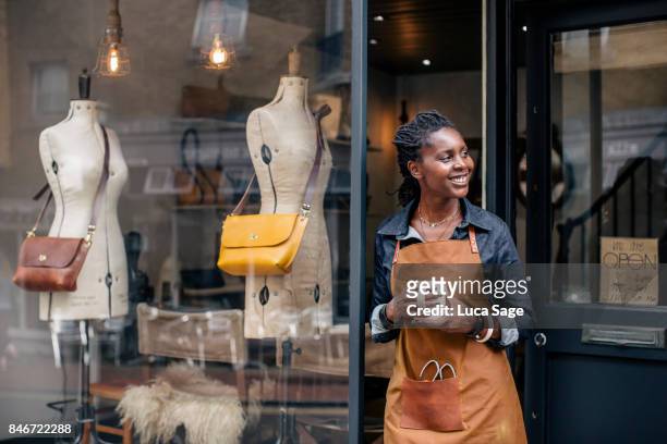 a small business owner stands outside her handbag shop. - unternehmer stock-fotos und bilder
