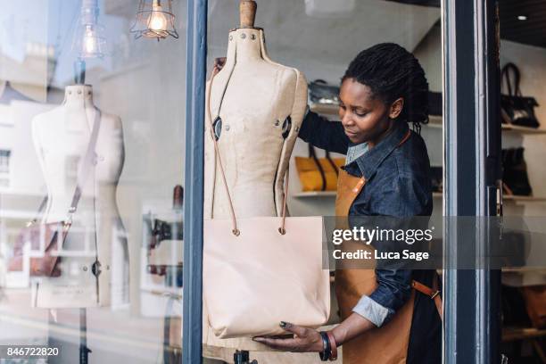 a handmade handbag store owner dresses her shop window - mannekin pis photos et images de collection