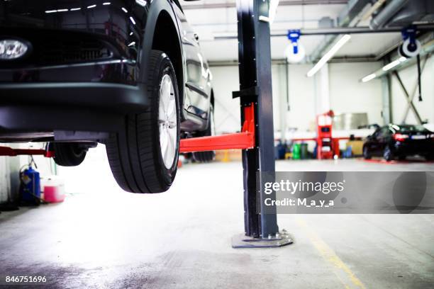 car on lift at car service - retrieving imagens e fotografias de stock