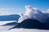 White smoke coming out of mount Bromo behind mount Batok in Indonesia.