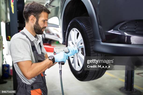 tire changing at car service - turning imagens e fotografias de stock