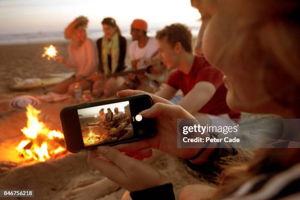 group of young people having fire on beach in the evening - beach photos stock-fotos und bilder