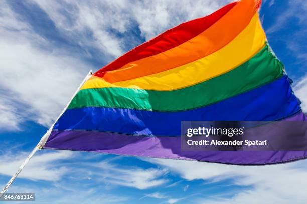rainbow flag waiving in the wind against blue sky - regenbogenfahne stock-fotos und bilder