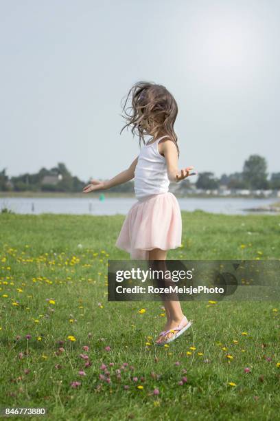 little girl jumping on a field of flowers - meisje stock-fotos und bilder