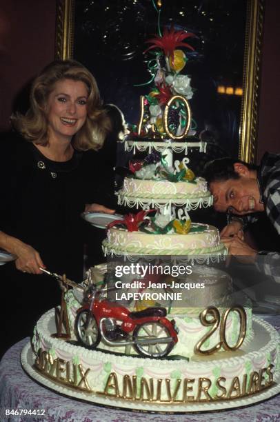 Catherine Deneuve decoupe un enorme gateau d'anniversaire lors de la fete de ses 40 ans avec son fils Christian le 27 octobre 1983 a Paris, France.