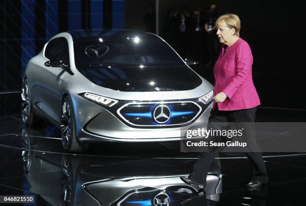 German Chancellor Angela Merkel walks past a Mercedes Concept EQA electric car while visiting the Mercedes hall at the 2017 IAA Frankfurt Auto Show...