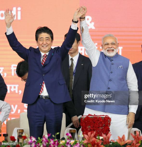 Japanese Prime Minister Shinzo Abe and Indian Prime Minister Narendra Modi raise their hands in Ahmadabad, India, on Sept. 14 during the ground...