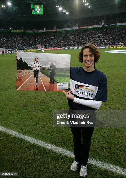 German Olympic gold medalist in pentathlon Lena Schoeneborn holds a poster which pictures herself and a VfL Wolfsburg football coach Felix Magath to...