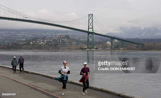 Joggers run along the Stanley Park seawall with the Lionsgate Bridge in the background February 7, 2009 in Vancouver, British Columbia. Vancouver...