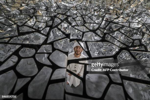 An Emirati man looks at the ceiling of a glass art installation commemorating the 2017 "Year of Giving" initiative declared by UAE President Sheikh...