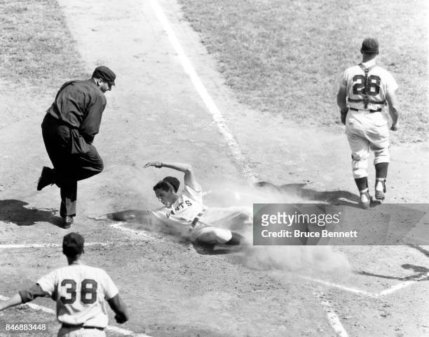 Bobby Thomson of the New York Giants slides safely into home as catcher Andy Seminick and pitcher Bud Podbielan of the Cincinnati Redlegs wait for...