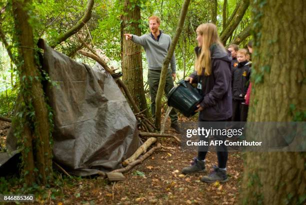 Britain's Prince Harry reacts as he takes part in a shelter building excercise with pupils from Felsted School during his visit to Chatham Green...