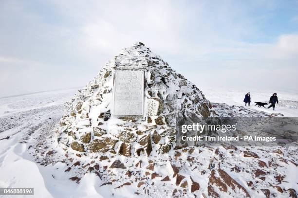 People walk their dog past Dunkery Beacon at the top of Dunkery Hill on Exmoor in Somerset as the cold weather continues across the UK.