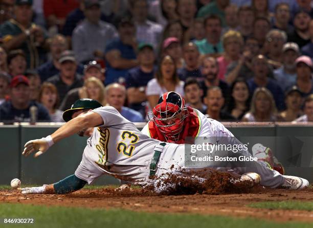 Oakland Athletics right fielder Matt Joyce slides into home plate safely as Boston Red Sox catcher Sandy Leon can't handle the throw to home during...