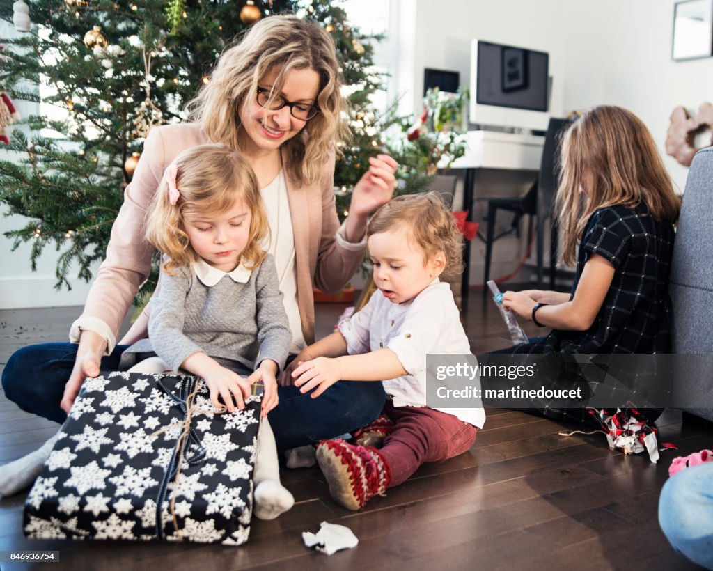 Abriendo regalos en la mañana de Navidad para familia pequeña.