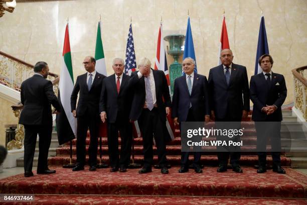 In his capacity as host, Britain's Foreign Secretary Boris Johnson, fourth left, adjusts his hair as he gets ready to pose for a group photograph...