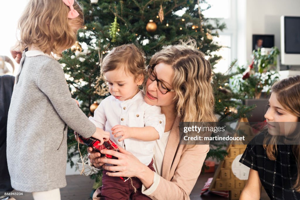 Öffnen die Geschenke am Weihnachtsmorgen für kleine Familie.