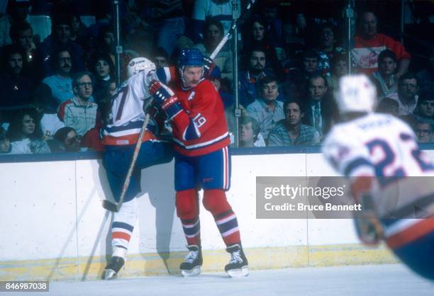 Larry Robinson of the Montreal Canadiens checks John Tonelli of the New York Islanders into the boards during an NHL game on March 4, 1986 at the...