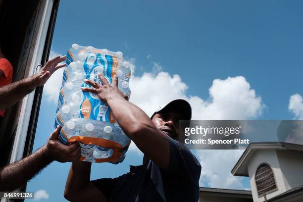 Water is passed out to residents in a rural migrant-worker town waiting for emergency donations following Hurricane Irma on September 14, 2017 in...