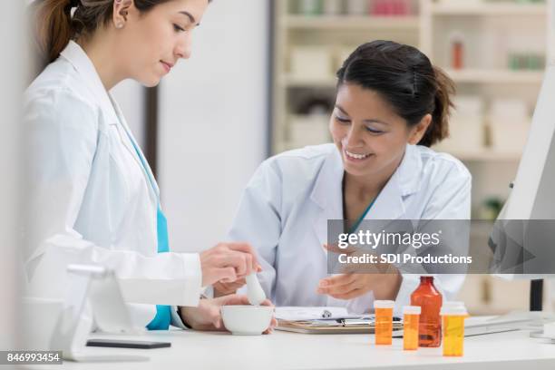 confident pharmacist uses a mortar and pestle in compounding pharmacy - pharmaceutical compounding stock pictures, royalty-free photos & images