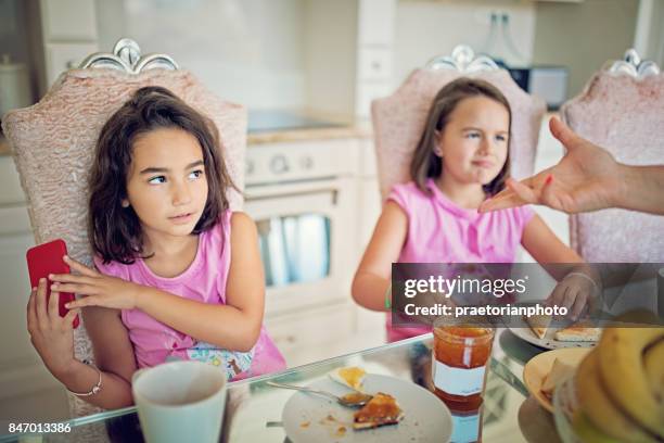 little girl is refusing to give mobile phone to her mother at the breakfast - angry parent mealtime stock pictures, royalty-free photos & images