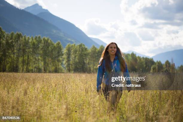 young indigenous canadian woman walking in a field - inuit people stock pictures, royalty-free photos & images