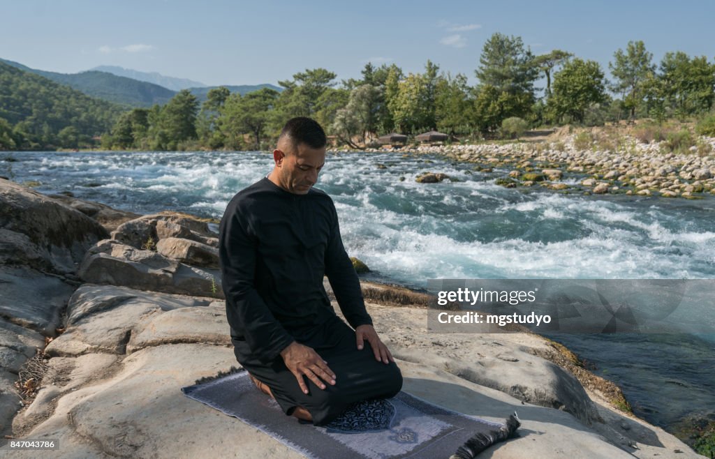 Young man praying outdoors in nature