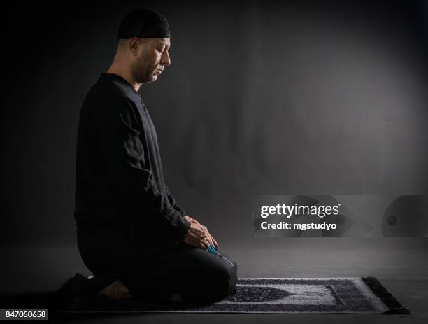 young man praying over black backround - muslim-praying stock pictures, royalty-free photos & images