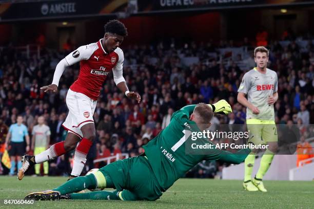 Cologne's German goalkeeper Timo Horn dives to make a save at the feet of Arsenal's English midfielder Ainsley Maitland-Niles during the UEFA Europa...