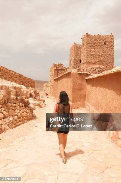 girl wearing walks next to a wall in a fortified construction - morocco tourist stock pictures, royalty-free photos & images