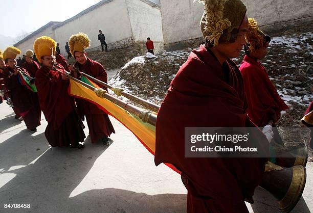 Lamas blow long trumpet on their way to send evil spirits which have been "killed", during the "Tiaoqian" praying ceremony at the Youning Temple on...