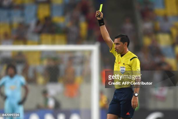 Referee Julio Quintana shows a yellow card to Jonathan Gonzales of Ecuador's Liga de Quito during their 2017 Sudamericana Cup football match held at...