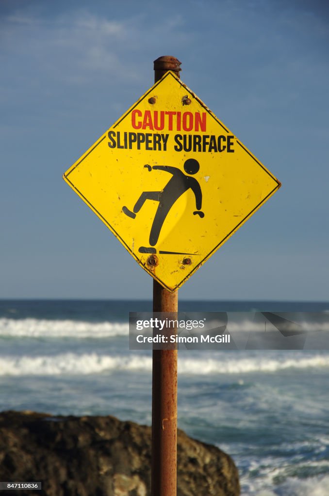 'Caution Slippery Rocks' warning sign next to Sawtell Memorial Rock Pool, Sawtell, New South Wales, Australia