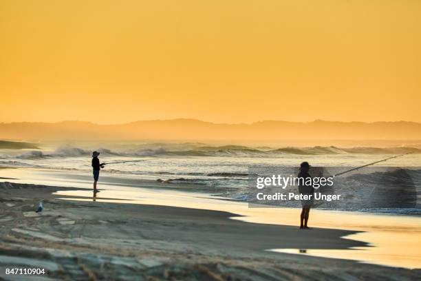 men fishing at sunset,north stradbroke island,queensland,australia - brisbane beach stock pictures, royalty-free photos & images
