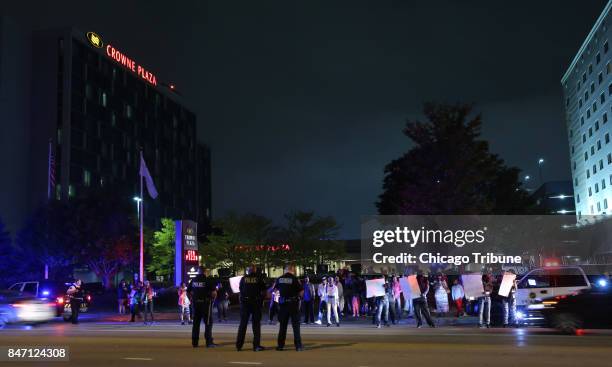 Protesters chant slogans as police officers stand guard at the Crowne Plaza Chicago O'Hare Hotel & Conference Center on September 13 in Rosemont,...