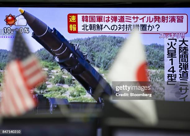 American and Japanese flags are displayed in front of a monitor showing a news broadcast of North Korea's missile launch at a foreign exchange...