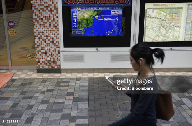 Pedestrian walks past a television screen displaying a map of Japan and the Korean Peninsula in a news program reporting on North Korea's missile...