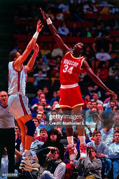 Hakeem Olajuwon of the Houston Rockets goes for a block against Sam Bowie of the New Jersey Nets during a game in 1991 at The Meadowlands Arena in...