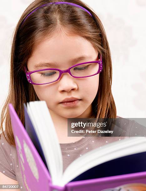 mixed race girl in purple glasses reading book. - parsons green stock pictures, royalty-free photos & images