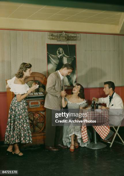 Two young couples eat out at a diner, circa 1955.