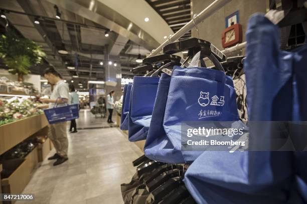Shopping bags used to fill online orders hang on a rack at an Alibaba Group Holding Ltd. Hema Store in Shanghai, China, on Tuesday, Sept. 12, 2017....