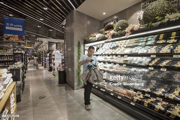 An employee carries shopping bags used to fill online orders at an Alibaba Group Holding Ltd. Hema Store in Shanghai, China, on Tuesday, Sept. 12,...