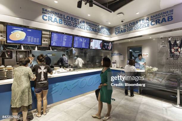 Customers wait in the kitchen area for freshly prepared dishes at an Alibaba Group Holding Ltd. Hema Store in Shanghai, China, on Tuesday, Sept. 12,...